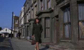 Movie still from “10 Rillington Place” (1971), directed by Richard Fleischer – A woman is walking down the street with a purse in her hand; Wide shot, Low angle