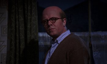 Movie still from “10 Rillington Place” (1971), directed by Richard Fleischer – A bald man wearing glasses and wearing a sweater; Close Up shot, Low angle