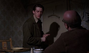 Movie still from “10 Rillington Place” (1971), directed by Richard Fleischer – A man is talking to another man in a room; Medium shot, Over the shoulder angle