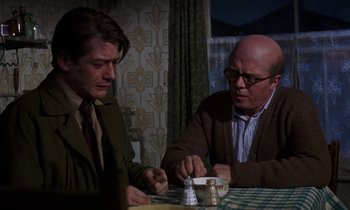 Movie still from “10 Rillington Place” (1971), directed by Richard Fleischer – Two men sitting at a table with a bowl of food; Medium shot, Over the shoulder angle