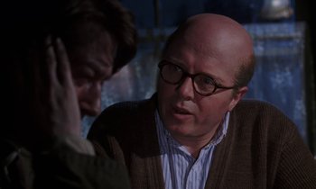 Movie still from “10 Rillington Place” (1971), directed by Richard Fleischer – A bald man wearing glasses talking to another man; Close Up shot, Over the shoulder angle
