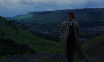 Movie still from “10 Rillington Place” (1971), directed by Richard Fleischer – A man standing on top of a hill wearing a trench coat; Wide shot, High angle