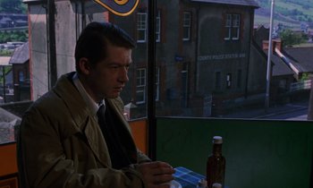 Movie still from “10 Rillington Place” (1971), directed by Richard Fleischer – A man sitting at a table in front of a window; Medium shot, Over the shoulder angle