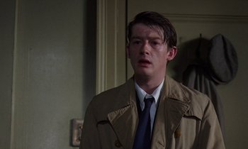 Movie still from “10 Rillington Place” (1971), directed by Richard Fleischer – A man wearing a trench coat and tie; Close Up shot, Over the shoulder angle