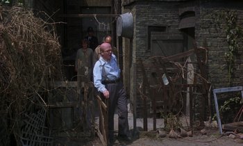 Movie still from “10 Rillington Place” (1971), directed by Richard Fleischer – An old man standing next to a wooden fence; Wide shot, High angle
