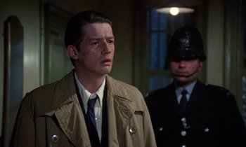 Movie still from “10 Rillington Place” (1971), directed by Richard Fleischer – A man in a trench coat and tie next to another man in a uniform; Close Up shot, Over the shoulder angle