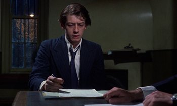 Movie still from “10 Rillington Place” (1971), directed by Richard Fleischer – A man sitting at a table writing on a piece of paper; Close Up shot, Over the shoulder angle