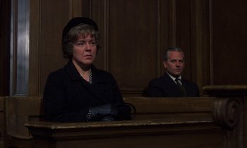 Movie still from “10 Rillington Place” (1971), directed by Richard Fleischer – Two people sitting in a court room in front of a judge; Medium shot, Low angle