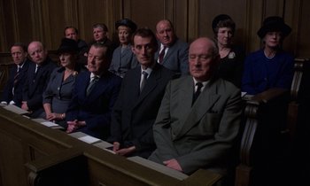 Movie still from “10 Rillington Place” (1971), directed by Richard Fleischer – A group of men in suits and ties sitting in front of a podium; Medium shot, High angle