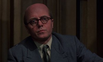 Movie still from “10 Rillington Place” (1971), directed by Richard Fleischer – A bald man in a suit and tie; Close Up shot, Over the shoulder angle