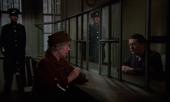 Movie still from “10 Rillington Place” (1971), directed by Richard Fleischer – An older woman sitting next to a man in a prison cell; Medium shot, Over the shoulder angle