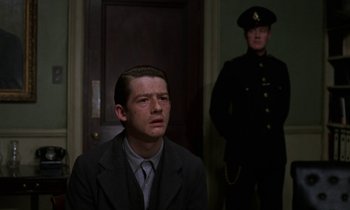Movie still from “10 Rillington Place” (1971), directed by Richard Fleischer – A man in a suit and tie next to a man in a uniform; Medium shot, Low angle