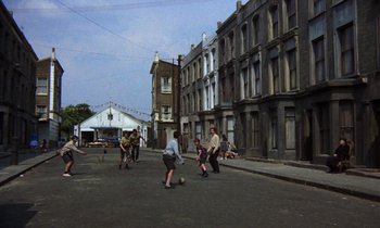 Movie still from “10 Rillington Place” (1971), directed by Richard Fleischer – A group of people playing soccer on a street; Wide shot, High angle