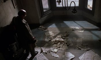 Movie still from “10 Rillington Place” (1971), directed by Richard Fleischer – A man standing in a room with papers on the floor; Wide shot, High angle
