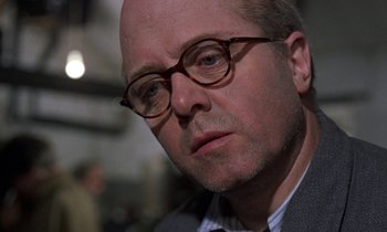 Movie still from “10 Rillington Place” (1971), directed by Richard Fleischer – A man wearing glasses and a suit and tie; Close Up shot, Over the shoulder angle