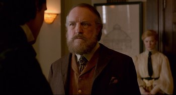 Movie still from “Crimson Peak” (2015), directed by Guillermo del Toro – An older man with a beard wearing a suit and tie; Close Up shot, Over the shoulder angle