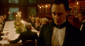 Movie still from “Crimson Peak” (2015), directed by Guillermo del Toro – A group of people sitting around a table; Medium shot, Over the shoulder angle