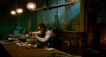 Movie still from “Crimson Peak” (2015), directed by Guillermo del Toro – A man and a woman sitting at a wooden table; Medium shot, High angle