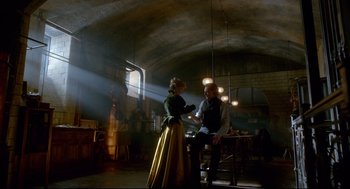 Movie still from “Crimson Peak” (2015), directed by Guillermo del Toro – A man and a woman standing in a dimly - lit room; Wide shot, Low angle