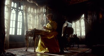 Movie still from “Crimson Peak” (2015), directed by Guillermo del Toro – A woman in a yellow dress sitting at a table; Wide shot, Low angle