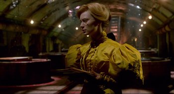 Movie still from “Crimson Peak” (2015), directed by Guillermo del Toro – A woman in a yellow dress is holding a book; Medium shot, Low angle