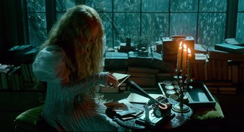 A woman sitting at a table with a candle and papers