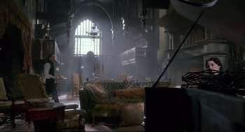 Movie still from “Crimson Peak” (2015), directed by Guillermo del Toro – A living room filled with lots of furniture and a large window; Extreme Wide shot, High angle