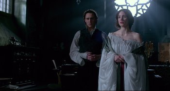 Movie still from “Crimson Peak” (2015), directed by Guillermo del Toro – A man and a woman standing next to each other in a dark room; Medium shot, Low angle