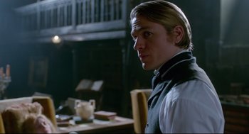 Movie still from “Crimson Peak” (2015), directed by Guillermo del Toro – A man in a vest standing in front of a table; Medium shot, Over the shoulder angle