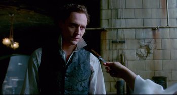 Movie still from “Crimson Peak” (2015), directed by Guillermo del Toro – A person holding a knife over a man's face; Medium shot, Over the shoulder angle