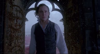 Movie still from “Crimson Peak” (2015), directed by Guillermo del Toro – A man standing in front of an archway in a forest; Medium shot, Low angle