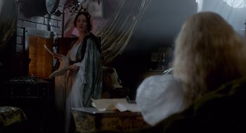 Movie still from “Crimson Peak” (2015), directed by Guillermo del Toro – A woman dressed in medieval garb standing in front of an open book; Medium shot, Over the shoulder angle