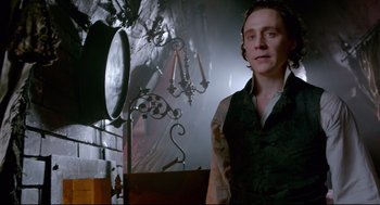 Movie still from “Crimson Peak” (2015), directed by Guillermo del Toro – A man standing in a room with a lot of stuff on the wall; Medium shot, Low angle