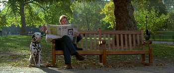 Movie still from “101 Dalmatians” (1996), directed by Stephen Herek – A man sitting on top of a wooden bench reading a newspaper; Medium shot, Low angle