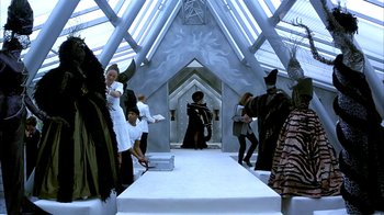 Movie still from “101 Dalmatians” (1996), directed by Stephen Herek – A group of people dressed as witches and wizards in front of a stage; Wide shot, High angle