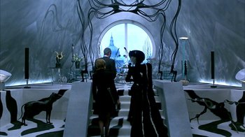 Two people are walking down the stairs in a room