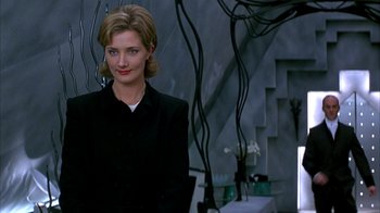 Movie still from “101 Dalmatians” (1996), directed by Stephen Herek – A woman in a black jacket standing in a room; Medium shot, Low angle