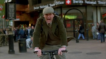 Movie still from “101 Dalmatians” (1996), directed by Stephen Herek – A man riding a bike with a hat on; Medium shot, Low angle