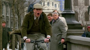 Movie still from “101 Dalmatians” (1996), directed by Stephen Herek – A man riding a bike on a city street; Medium shot, Low angle