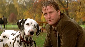 Movie still from “101 Dalmatians” (1996), directed by Stephen Herek – A man and a dalmatian sitting in the grass; Close Up shot, Low angle