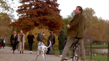 Movie still from “101 Dalmatians” (1996), directed by Stephen Herek – A man riding a bike with a dalmatian dog on a leash; Wide shot, Low angle