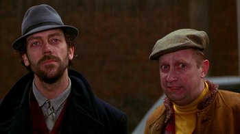 Movie still from “101 Dalmatians” (1996), directed by Stephen Herek – A man and a man in a hat and jacket; Close Up shot, Over the shoulder angle