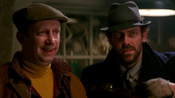 Movie still from “101 Dalmatians” (1996), directed by Stephen Herek – A couple of men standing next to each other; Close Up shot, Over the shoulder angle