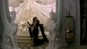 Movie still from “101 Dalmatians” (1996), directed by Stephen Herek – A woman dressed as a black swan next to a statue of a white dragon; Wide shot, High angle