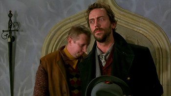 Movie still from “101 Dalmatians” (1996), directed by Stephen Herek – Two men standing next to each other in front of a wall; Close Up shot, Low angle