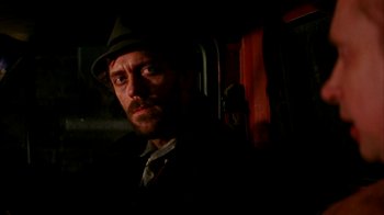 Movie still from “101 Dalmatians” (1996), directed by Stephen Herek – A man in a hat and a tie standing next to a train; Close Up shot, Over the shoulder angle