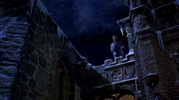 Movie still from “101 Dalmatians” (1996), directed by Stephen Herek – A man standing on the side of a building at night; Extreme Wide shot, Low angle