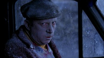Movie still from “101 Dalmatians” (1996), directed by Stephen Herek – A man in a hat and jacket looking out of a window; Close Up shot, High angle