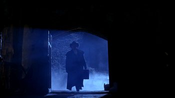 Movie still from “101 Dalmatians” (1996), directed by Stephen Herek – A man in a hat and a long coat walking through a tunnel; Wide shot, Low angle