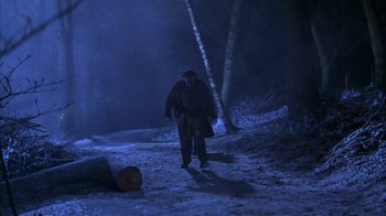Movie still from “101 Dalmatians” (1996), directed by Stephen Herek – A man walking on a path in the woods at night; Wide shot, High angle
